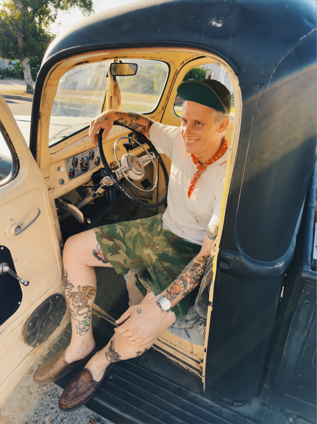 Person sitting inside a vintage car, looking at themselves in the mirror.