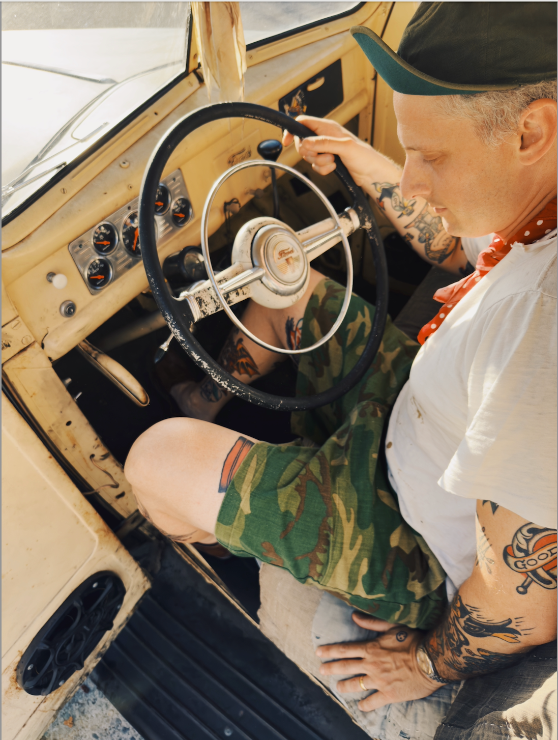 Person sitting inside an old car with a vintage steering wheel