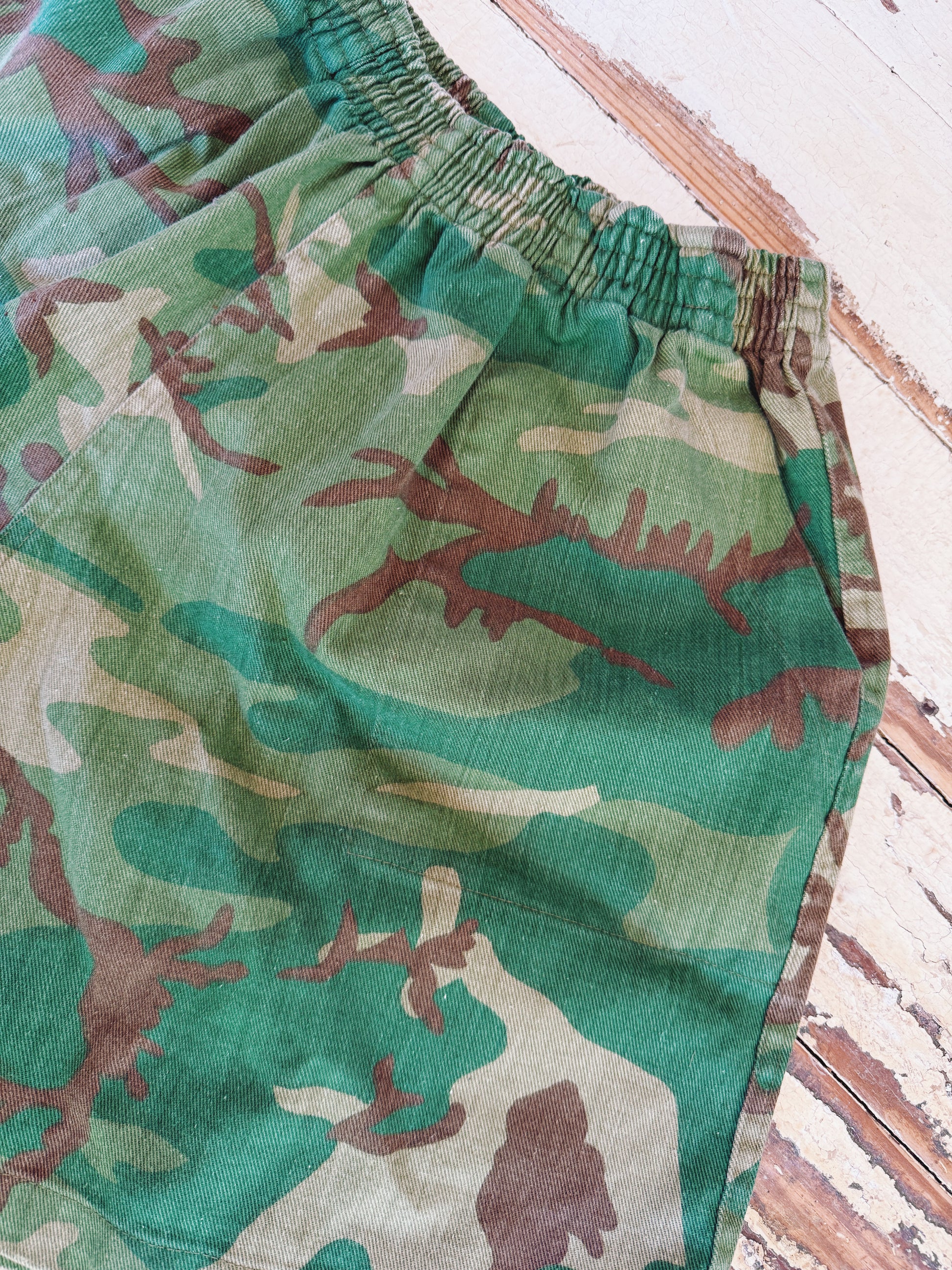 Camouflage-patterned shorts on a wooden surface