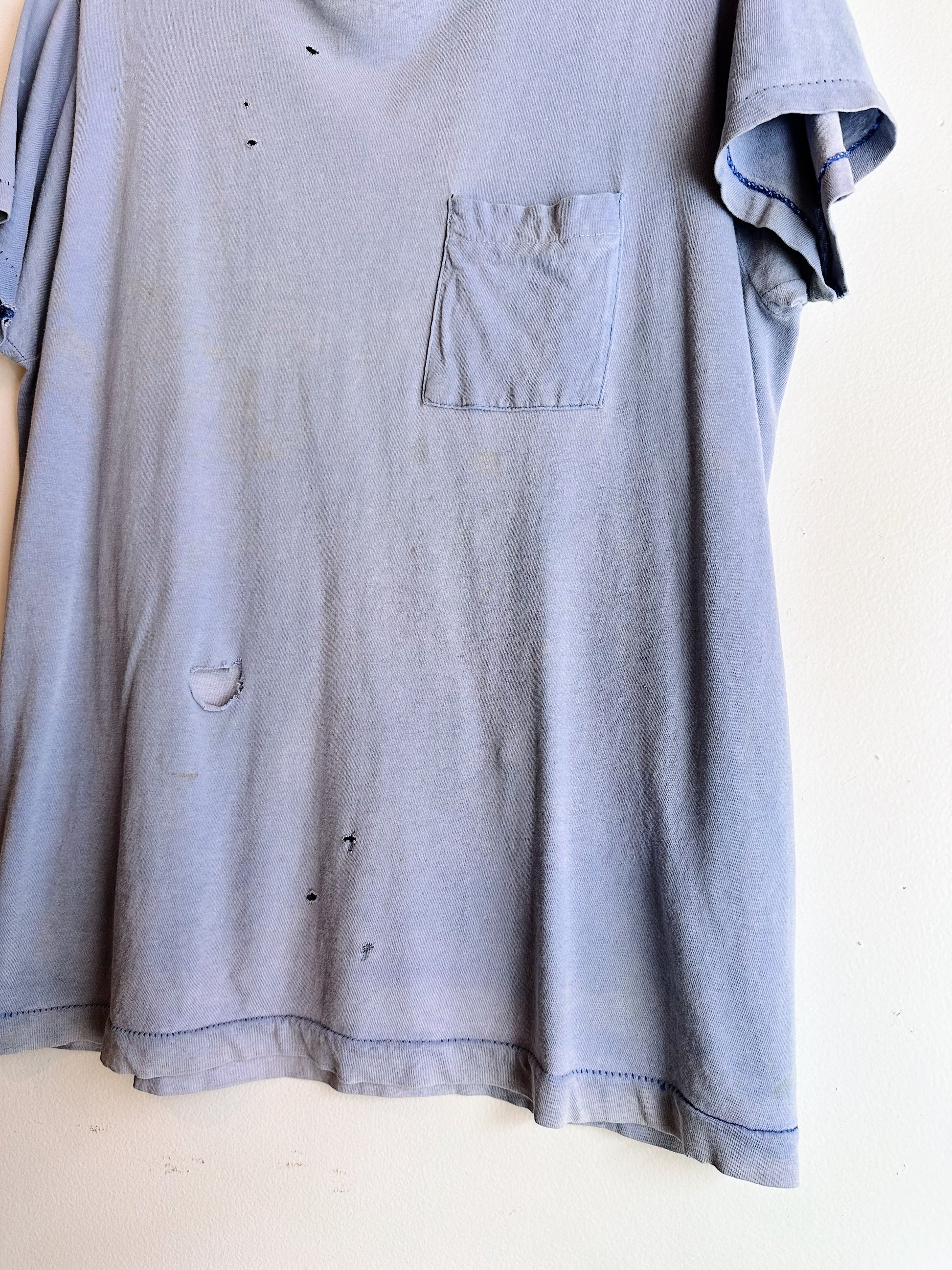 angled up view of bottom of t shirt with holes near seam 